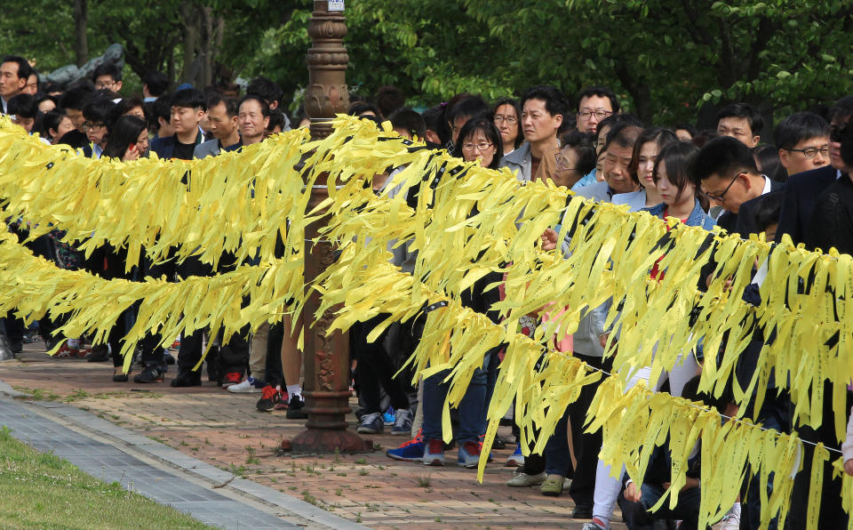 People wait to pay tribute to the victims of the sunken ferry Sewol as yellow ribbons with messages for missing passengers are displayed at a group memorial altar in Ansan, South Korea, Sunday, May 4, 2014. South Korean President Park Geun-hye told families of those missing in the sunken ferry that her heart breaks knowing what they are going through, as divers recovered two more bodies on Sunday. (AP Photo/Ahn Young-joon)