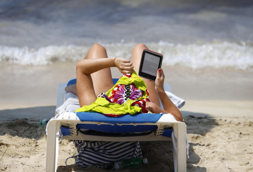 MUJER LEE EN LA PLAYA EN UN EBOOK FOTO: CLARA MARGAIS /GETTY IMAGES