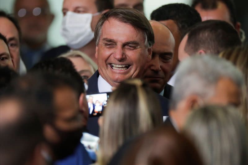 Brazil's President Jair Bolsonaro smiles near mayors after a ceremony to launch a program to help new mayors, at Planalto Palace in Brasilia