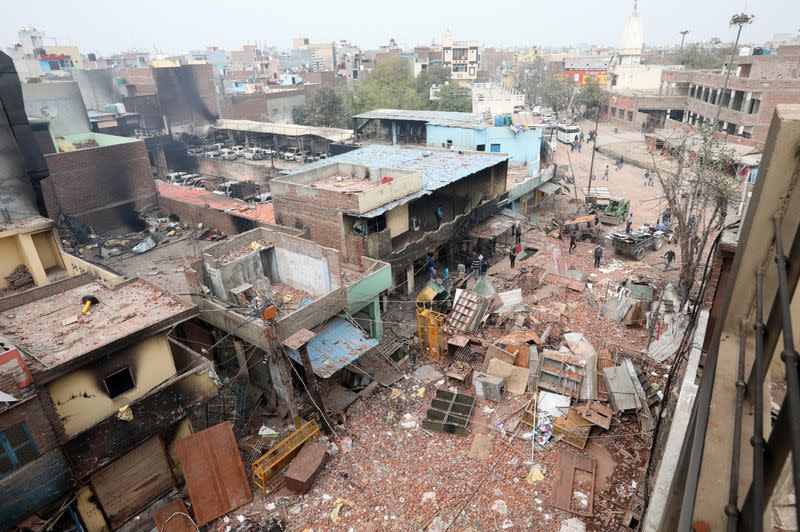 Men remove debris in a riot affected area following clashes between people demonstrating for and against a new citizenship law in New Delhi