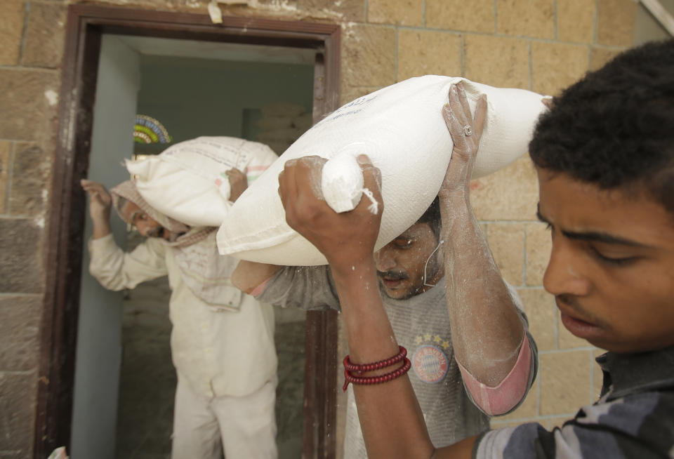 FILE - In this Aug. 25, 2019 file photo, workers carry food supplies provided by the World Food Programme for distribution, in Sanaa, Yemen. On Wednesday, Sept. 1, 2021, Yemeni and global rights groups accused both sides in the country’s civil war of using starvation as a tactic of war. They urged the U.N. Security Council to refer the opposing participants to the International Criminal Court to investigate alleged crimes in its years-long conflict. (AP Photo/Hani Mohammed, File)