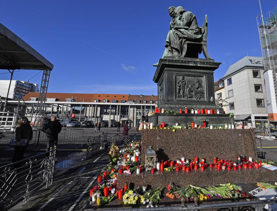 Flowers and candles are set around a monument for the brothers Grimm, Hanau's best known sons, on the market place in Hanau, Germany, Friday, Feb. 21, 2020 two days after a 43-year-old German man shot and killed several people at several locations in a Frankfurt suburb on Wednesday, Feb. 19, 2020. (AP Photo/Martin Meissner)