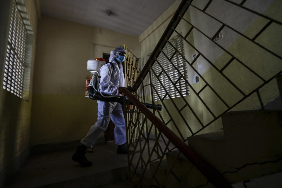 A civic staff in protective suit disinfects the staircase of an apartment where one of the residents tested positive for COVID-19 in Kolkata, India, Tuesday, Sept. 22, 2020. The nation of 1.3 billion people is expected to become the coronavirus pandemic's worst-hit country within weeks, surpassing the United States. (AP Photo/Bikas Das)