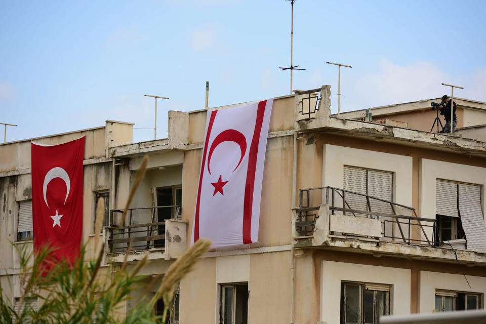 A police officer use binoculars is seen on a roof of an abandoned building before Turkish President Recep Tayyip Erdogan inspects the newly opened beachfront of Varosha in war-divided Cyprus' in the Turkish occupied area in the breakaway Turkish Cypriot north on Sunday, Nov. 15, 2020. Erdogan appeared to throw a fresh bid to restart dormant Cyprus reunification talks into doubt, saying that a two-state deal rather than the long-established federal formula is the way forward. (AP Photo/Nedim Enginsoy)