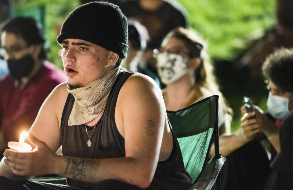 Jackson Cruitt sings during a vigil for John Neville on Wednesday, Aug. 5, 2020, in Bailey Park in Winston-Salem, N.C. Demonstrators held the vigil to demand justice for Neville, a Black man who died days after his December 2019 arrest following the release of body camera videos that showed him struggling with guards and yelling he couldn’t breathe as they restrained him. (Allison Lee Isley/The Winston-Salem Journal via AP)