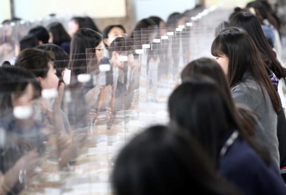 High school students eat lunch at a cafeteria with plastic screens on the table for preventing infection, as schools reopen following the global outbreak of the coronavirus disease (COVID-19), in Daejeon, South Korea, May 20, 2020. Yonhap/via REUTERS ATTENTION EDITORS - THIS IMAGE HAS BEEN SUPPLIED BY A THIRD PARTY. NO RESALES. NO ARCHIVE. SOUTH KOREA OUT. NO COMMERCIAL OR EDITORIAL SALES IN SOUTH KOREA.