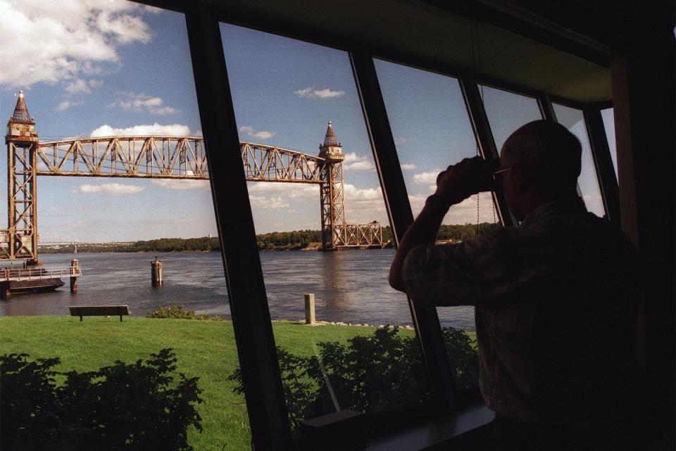 In a file photo, a marine traffic controller at the Cape Cod Canal, uses binoculars to look toward the railroad bridge that crosses the western end of the canal.