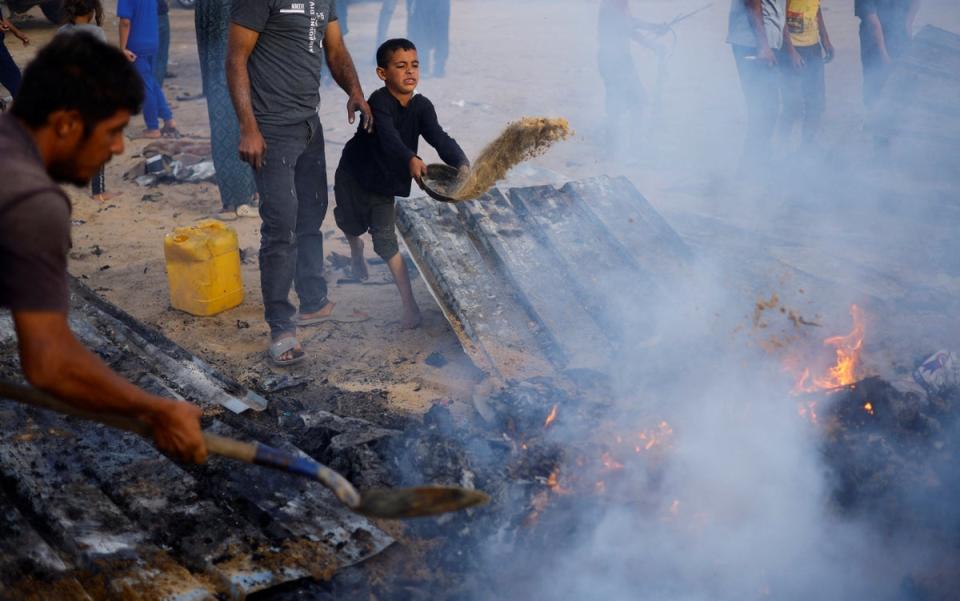 Palestinians put out a fire at the site of an Israeli strike on an area designated for displaced people in Rafah in the southern Gaza Strip on May 27 (Mohammed Salem/Reuters)