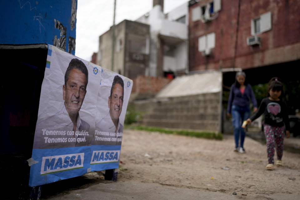 People walk near an election campaign poster promoting Economy Minister Sergio Massa, the ruling party’s presidential candidate, outside an office run by the Evita Movement, a Peronist social organization, in Cuidad Evita on the outskirts of Buenos Aires, Argentina, Monday, Nov. 13, 2023. As Argentina heads for a presidential Nov. 19 runoff election, the decades-old populist movement known as Peronism has Massa working overtime to keep once-steadfast supporters from straying to his opponent, right-wing populist Javier Milei. (AP Photo/Natacha Pisarenko)