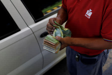 A gas station worker counts Venezuelan bolivar notes at a gas station of the Venezuelan state-owned oil company PDVSA in Caracas, Venezuela August 17, 2018. REUTERS/Marco Bello