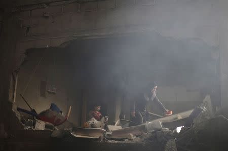 Smoke rises as a Palestinian woman inspects her house, which witnesses said was damaged by an Israeli air strike, in Rafah in the southern Gaza Strip August 24, 2014. REUTERS/Ibraheem Abu Mustafa