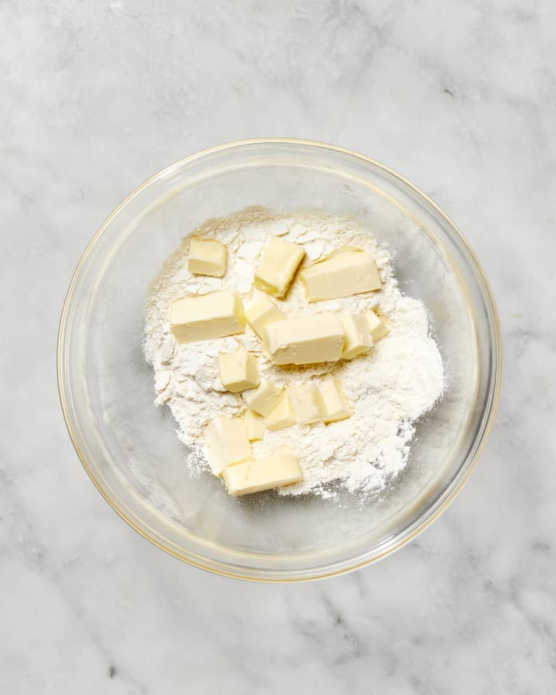 A bowl with flour and cubes of butter to make a pie crust seen from above.