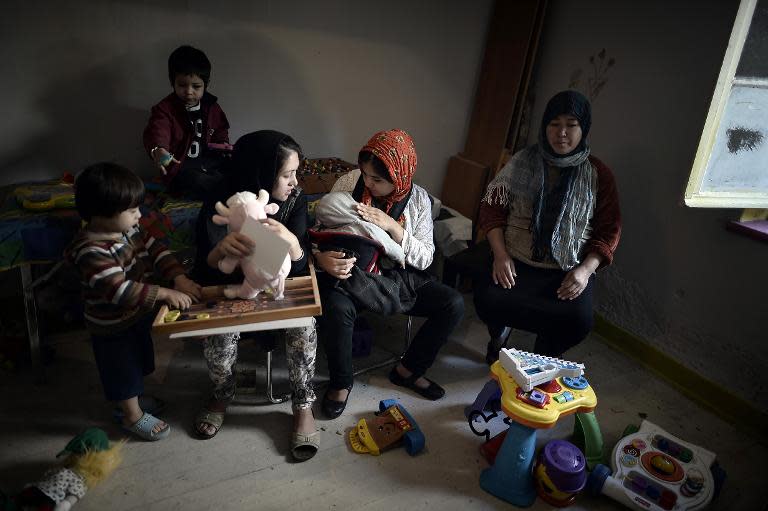 Women sit with their children at a playground room , run by Geek squatters at the Prosfygika complex in central Athens on November 2, 2014