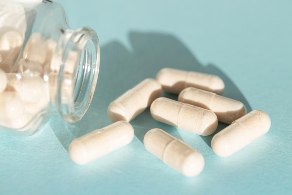 prebiotic capsules pouring from bottle on blue background