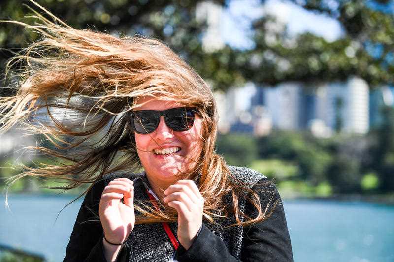 A tourist is buffeted by winds at Mrs Macquaries Road, Botanic Gardens, Sydney.