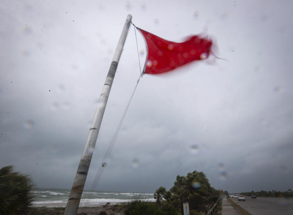 A red flag, warning of dangerous rip current activity, waves heavily in the wind as a squall line moves through Honeymoon Island State Park Thursday, April 11, 2024, in Dunedin, Fla. (Chris Urso/Tampa Bay Times via AP)