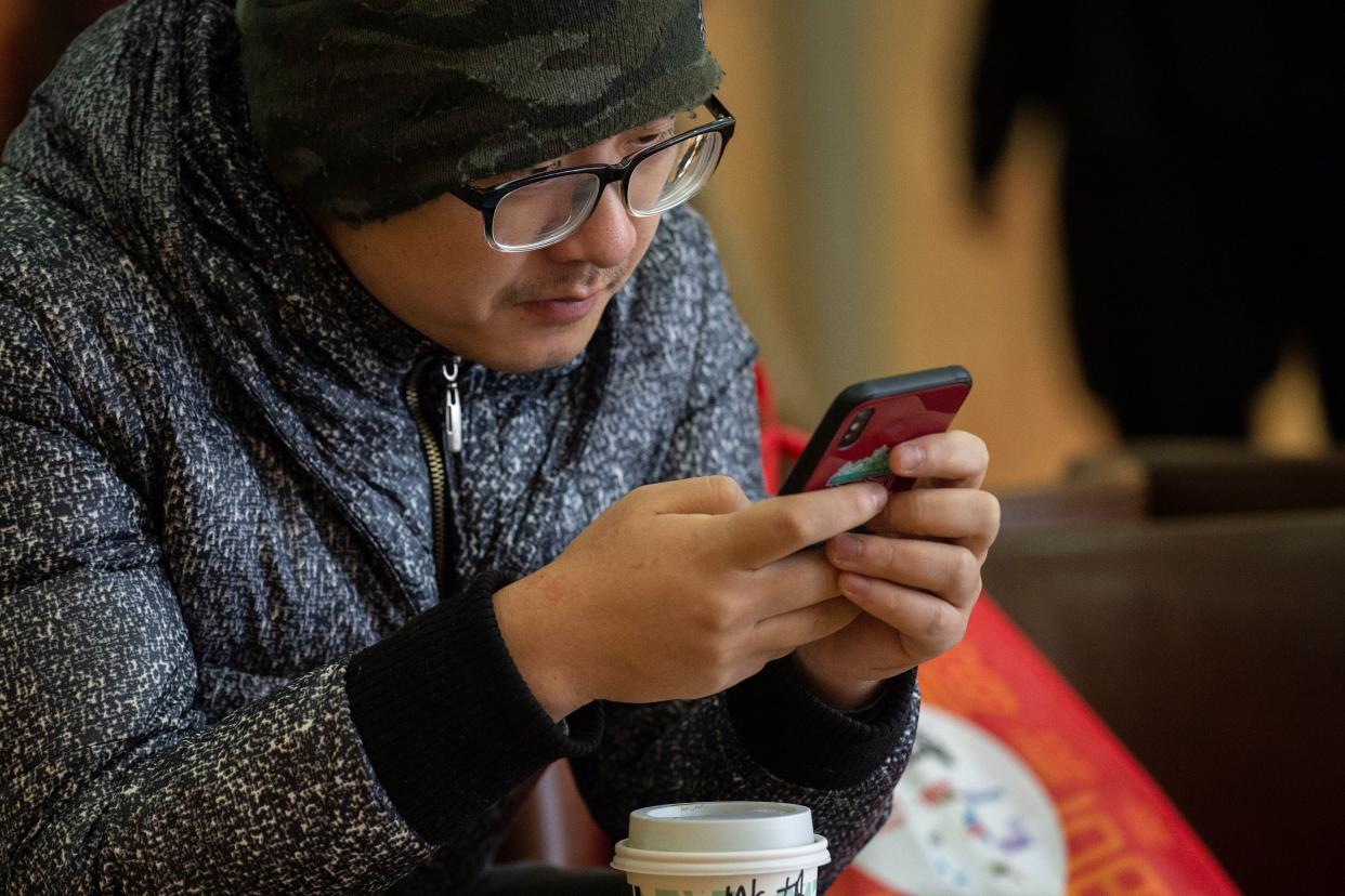 A man uses an Apple iPhone inside a shopping mall in Beijing on January 3, 2019. - Apple cut its revenue outlook for the latest quarter on January 3, citing steeper-than-expected 