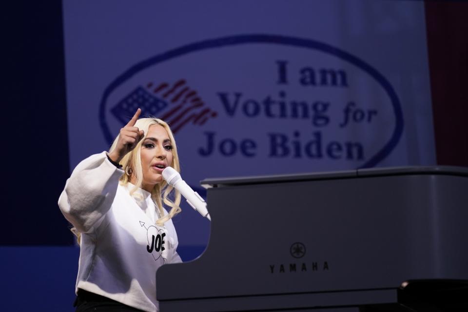 Lady Gaga at a piano and a screen behind her says, "I am voting for Joe Biden."