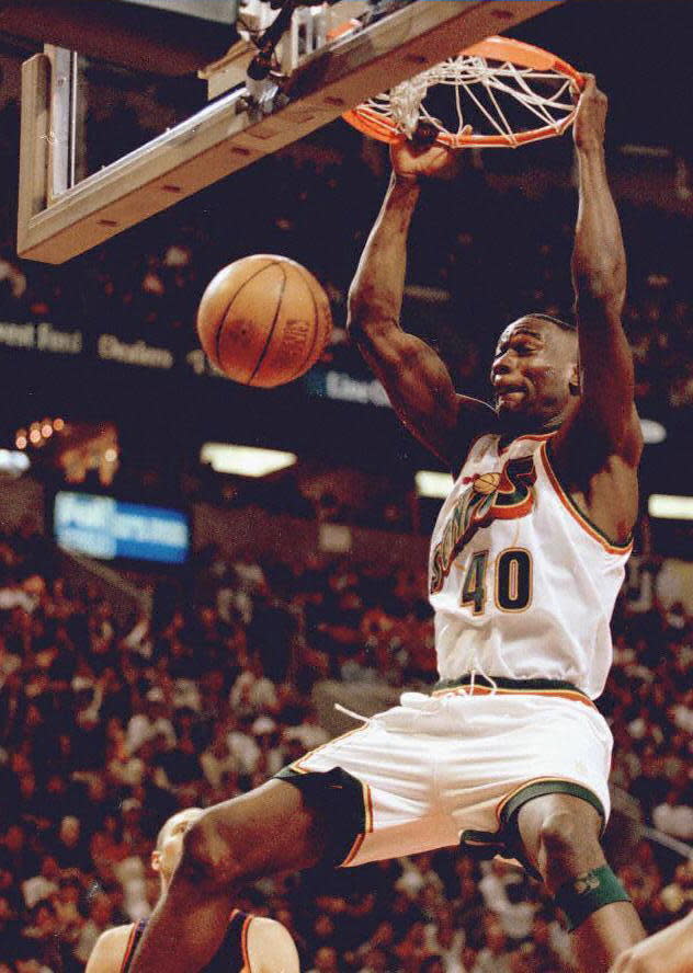 Seattle Sonics player Shawn Kemp slam dunks the ball against the Phoenix Suns in May 1997. / Credit: DAN LEVINE/AFP via Getty