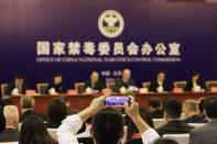 An attendee takes a photo of the press conference held by China's National Narcotics Control Commission in Beijing on Tuesday, May 11, 2021. China on Tuesday said it will add all synthetic cannabinoids to its list of banned drugs, in what it described as a first in the world, to curb their manufacturing, trafficking and abuse. (AP Photo/Ng Han Guan)