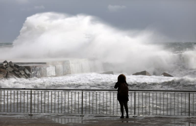 A woman looks at waves during the storm "Gloria" on Barceloneta beach, in Barcelona