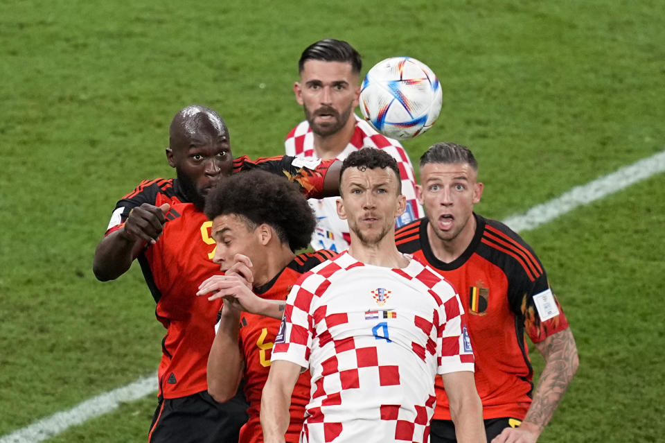 El croata Ivan Perisic (4) salta por el balón en medio de los belgas Romelu Lukaku (izquierda), Axel Witsel (abajo izquierda) y Toby Alderweireld (derecha) en el partido por el Grupo F del Mundial, el jueves 1 de diciembre de 2022. El croata Marko Livaja mira al fondo. (AP Foto/Ebrahim Noroozi)