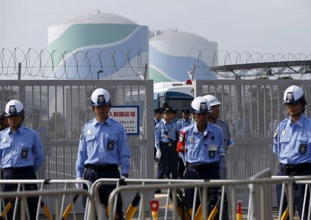 Police officers and security personnel stand guard at an entrance of Kyushu Electric Power's Sendai nuclear power station, during a protest demanding for the stop of the plant's restart, in Satsumasendai, Kagoshima prefecture, Japan August 9, 2015. REUTERS/Issei Kato/File Photo