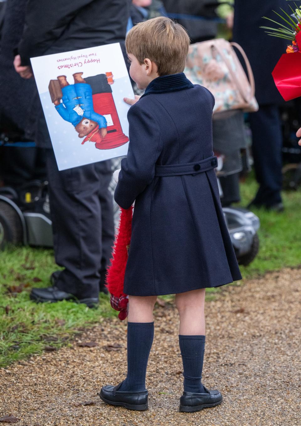 Prince Louis accepts a book from a member of the public in Sandringham on Christmas