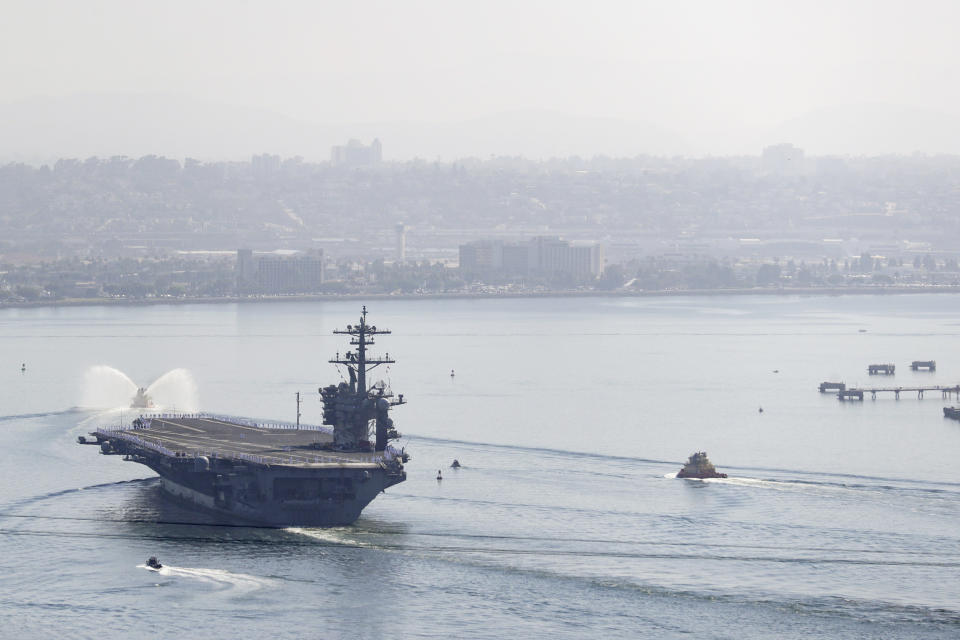 The USS Theodore Roosevelt aircraft carrier makes its way into San Diego Bay Thursday, July 9, 2020, seen from San Diego. The carrier returned home to San Diego Thursday, led by a new captain who came aboard after the previous commander was fired and the Navy secretary resigned over the handling of a massive COVID-19 outbreak on board. (AP Photo/Gregory Bull)