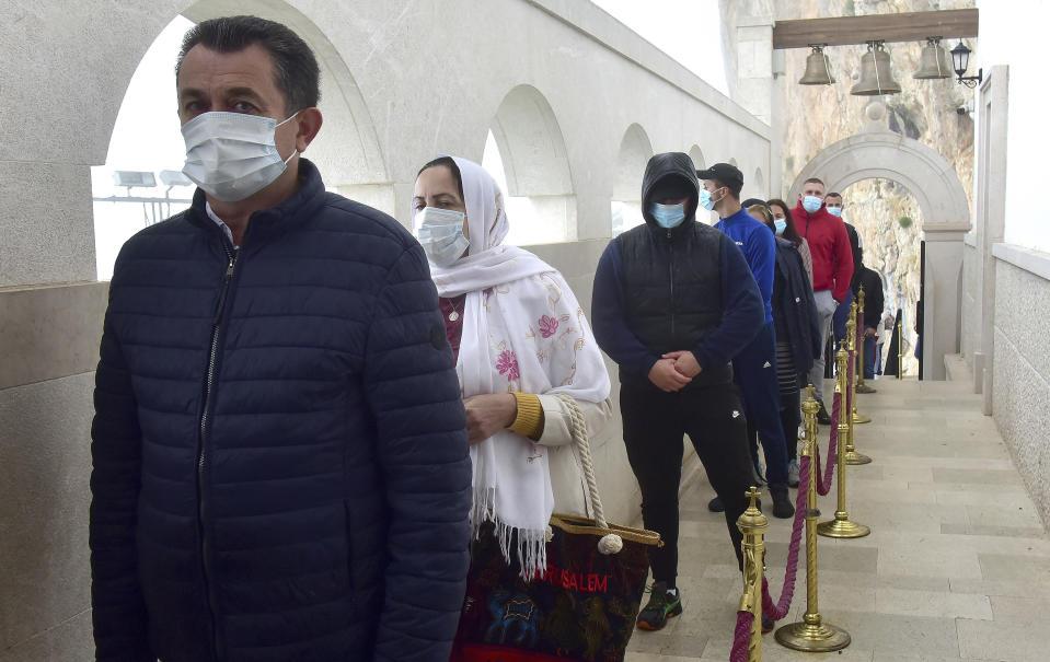 Believers wearing a mask against the spread of the new coronaviru wait in a queue in front of the Christian Orthodox monastery of Ostrog, 30 kilometers northwest of the Montenegrin capital Podgorica, May 12, 2020. Serbian Orthodox Church is going ahead with annual pilgrimage to the Ostrog monastery to mark St Basil's Day despite a ban on social gatherings. (AP Photo/Risto Bozovic)