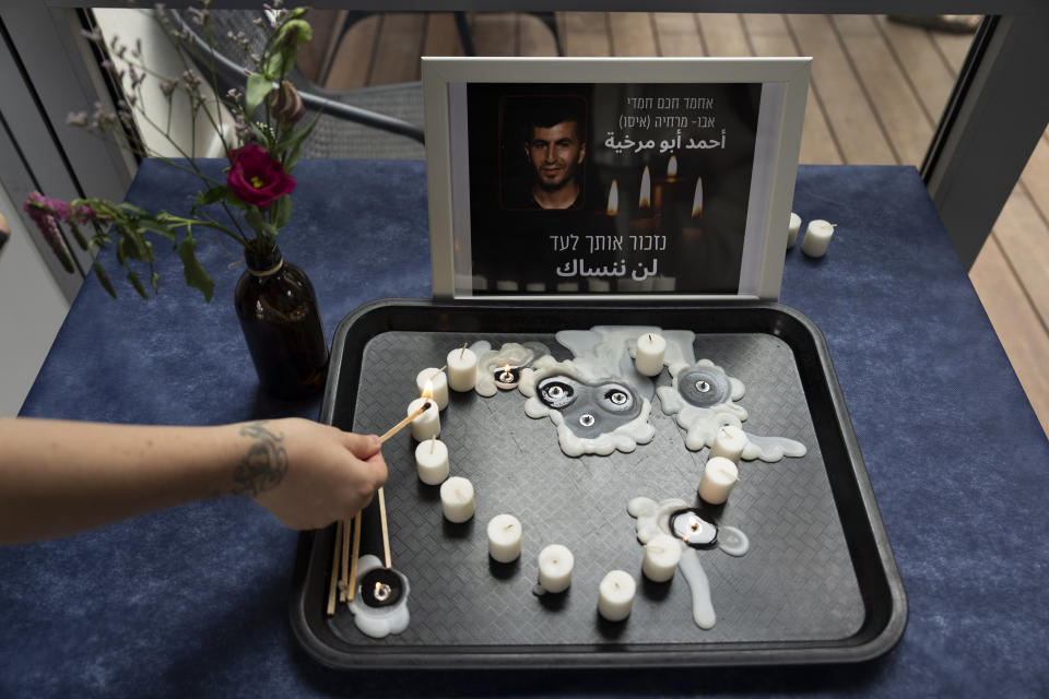 A volunteer lights a candle during a vigil for Ahmad Abu Murkhiyeh, a 25-year-old Palestinian man who was found decapitated in the West Bank city of Hebron, at an LGBTQ shelter in Tel Aviv, Israel, Oct. 7, 2022. Accounts that Abu Murkhiyeh was a gay man who had sought asylum in Israel has turned the tragedy into a socially and politically explosive case, reflecting divergent views from two very different societies. Hebrew and Arabic reads "we will remember you forever". (AP Photo//Oded Balilty)