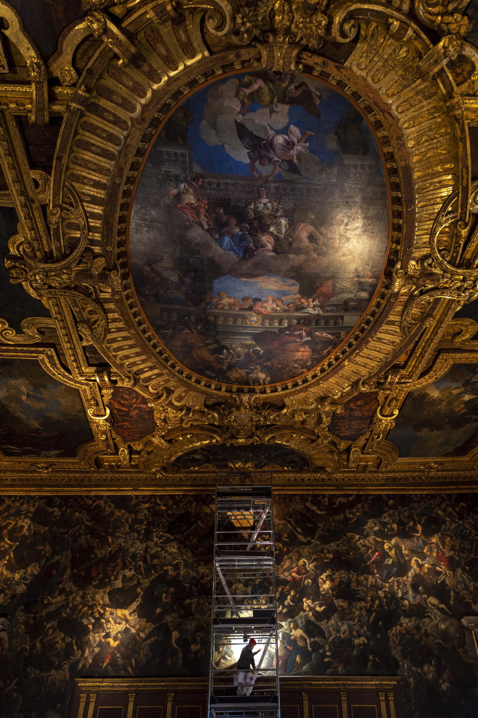 Restorer Alberto Marcon inspects the 7,45x24,65-meter oil on canvas 'Il Paradiso' completed in 1592 by Venetian painters Jacopo Robusti, also known as Tintoretto, and his son Domenico in the Maggior Consiglio Hall inside Palazzo Ducale in Venice, northern Italy, Wednesday, Dec. 6, 2022. The Doge's Palace, the heart of the political life of the Venetian Republic for centuries, is undergoing a major reconnaissance of its conservation status by the Fondazione Musei Civici of the municipality of Venice that includes the urgent restoration of its paintings and infrastructures, which is expected to be completed in the summer of 2023. (AP Photo/Domenico Stinellis)