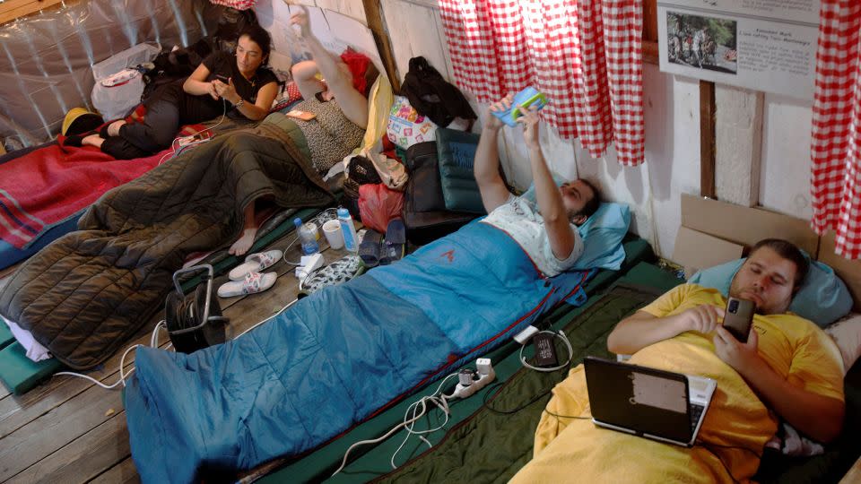 Participants use their phones inside a hut, during a satirical contest to mock a popular myth that labels Montenegrins as lazy. - Stevo Vasiljevic/Reuters