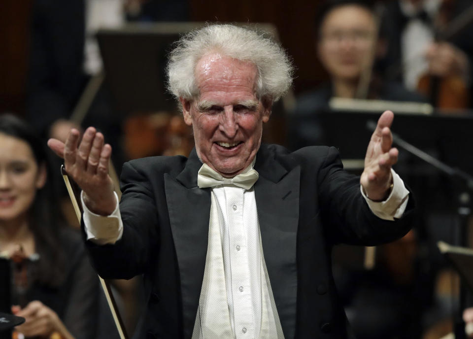 In this Feb. 14, 2019 photo, conductor Benjamin Zander gestures praise for members of the Boston Philharmonic Orchestra at the Sanders Theatre in Cambridge, Mass. The internationally acclaimed conductor, who approaches his 80th birthday on March 9, has spent half his life leading the Boston Philharmonic Orchestra, which he founded in 1979. (AP Photo/Elise Amendola)