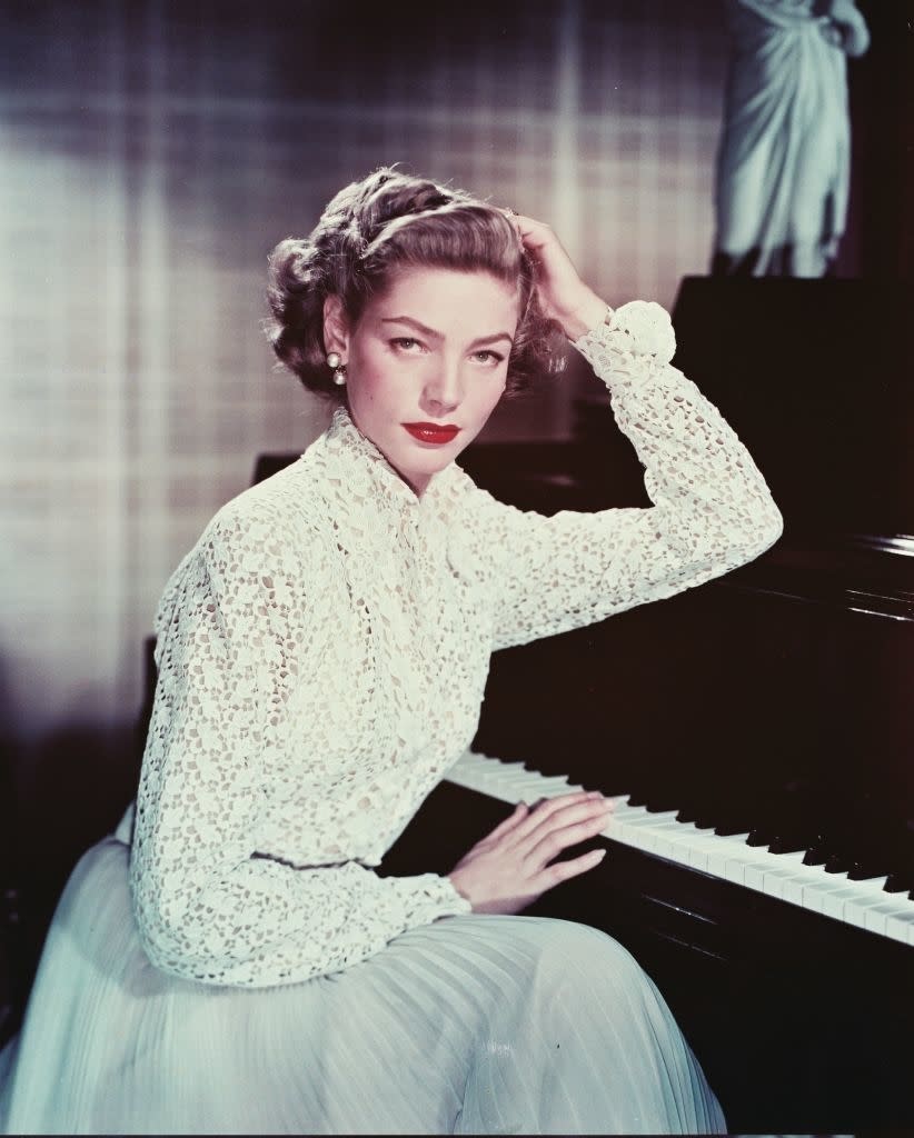 Lauren seated at a piano wearing a lace top and full skirt