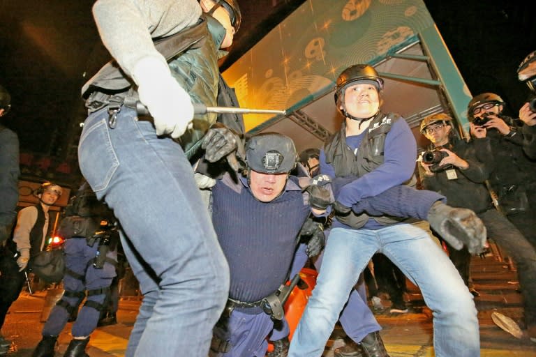 Hong Kong police assist an injured colleague when battles erupted after officials tried to move illegal food sellers from an area in Mongkok during the Lunar New Year holiday in Hong Kong