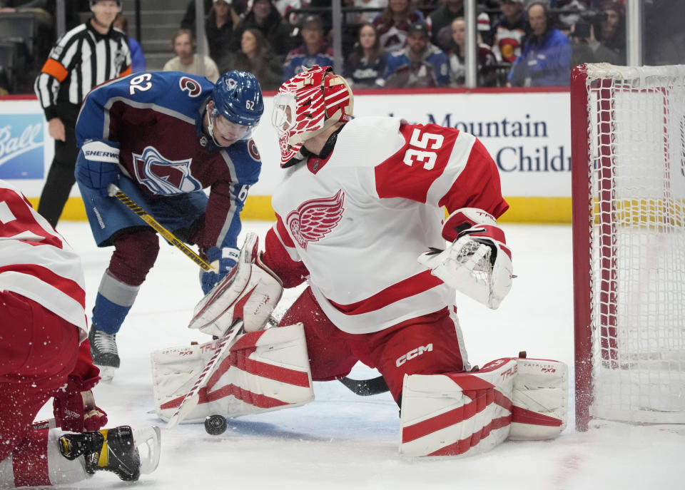Detroit Red Wings goaltender Ville Husso, front, stops the puck as Colorado Avalanche left wing Artturi Lehkonen drives to the net in the first period of an NHL hockey game, Monday, Jan. 16, 2023, in Denver. (AP Photo/David Zalubowski)