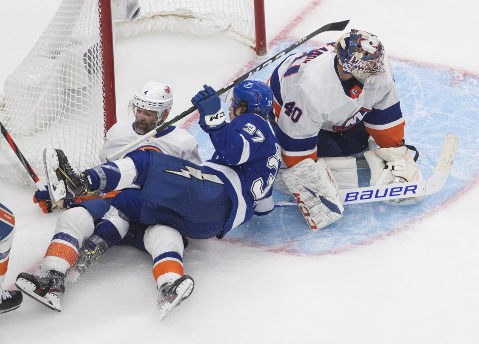 Tampa Bay Lightning left wing Yanni Gourde (37) and New York Islanders defenseman Andy Greene (4) crash into the net as Islanders goaltender Semyon Varlamov (40) looks for the puck during the second overtime in Game 5 of the NHL hockey Eastern Conference final, Tuesday, Sept. 15, 2020, in Edmonton, Alberta. (Jason Franson/The Canadian Press via AP)
