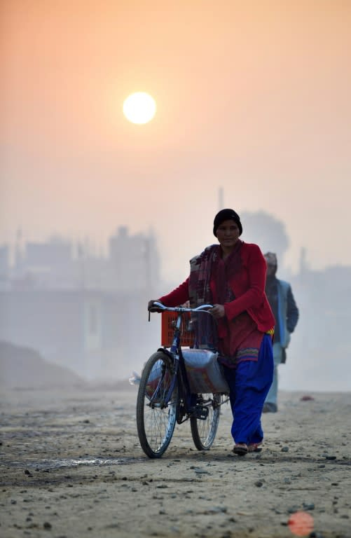 Vegetable vendor Nandukula Basnet, 33, arrives on her bicycle to sell her wares at a Nepali market in February