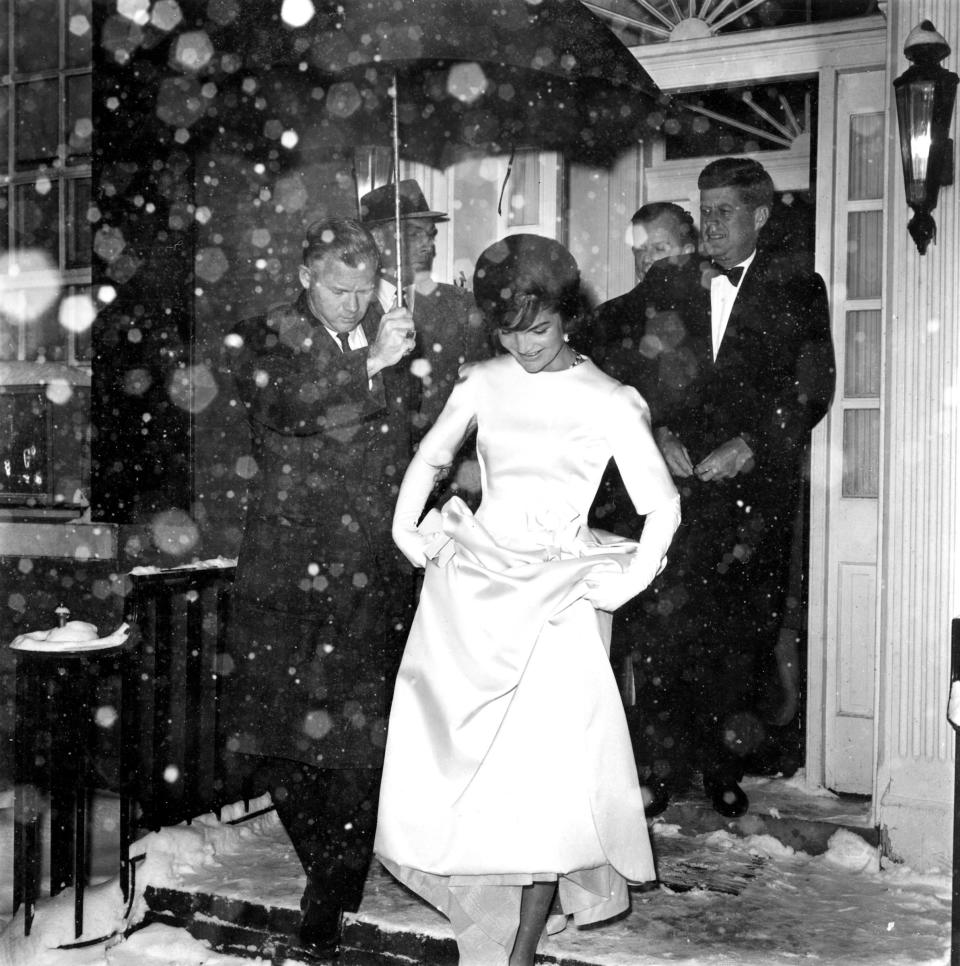 Jacqueline Kennedy lifts the skirt of her inaugural ball gown as she and her husband, President-elect John F. Kennedy, leave their Georgetown home in the snowfall en route to the inaugural concert in Washington, D.C., Jan. 19, 1961. (AP Photo)