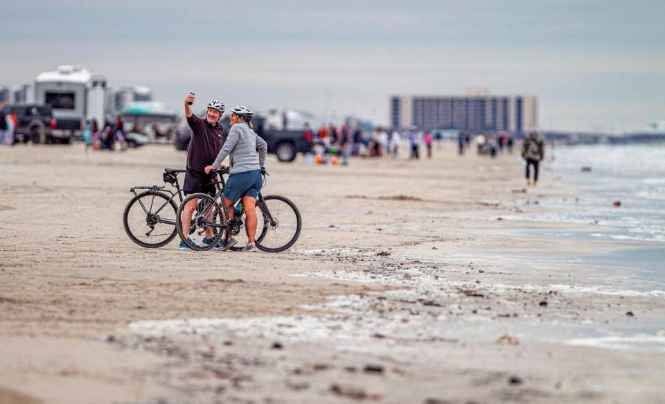 A couple on bicycles take a snapshot of themselves on the sand. Many Texans spent their Thanksgiving Day on the beach in Port Aransas Thursday, Nov. 23, 2023. DAVID MONTESINO/dmontesino@star-telegram.com