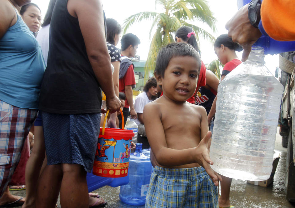 A boy fills up a plastic bottle with water after super typhoon Haiyan hit Tacloban