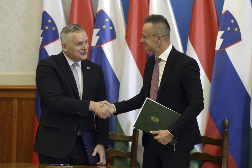 Slovenian Minister for the Environment, Climate and Energy, Bojan Kumer, left, and Hungarian Minister of Foreign Affairs and Trade Peter Szijjarto, right, shake hands after signing a strategic partnership during their meeting in Budapest, Hungary, Wednesday, Oct. 4, 2023. (Attila Kovacs/MTI via AP)