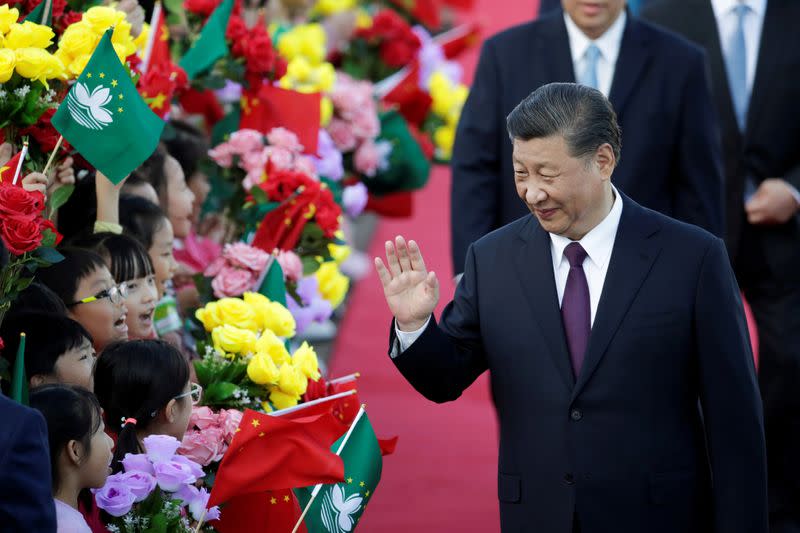 Chinese President Xi Jinping waves at children holding Chinese and Macau flags after arriving at Macau International Airport in Macau