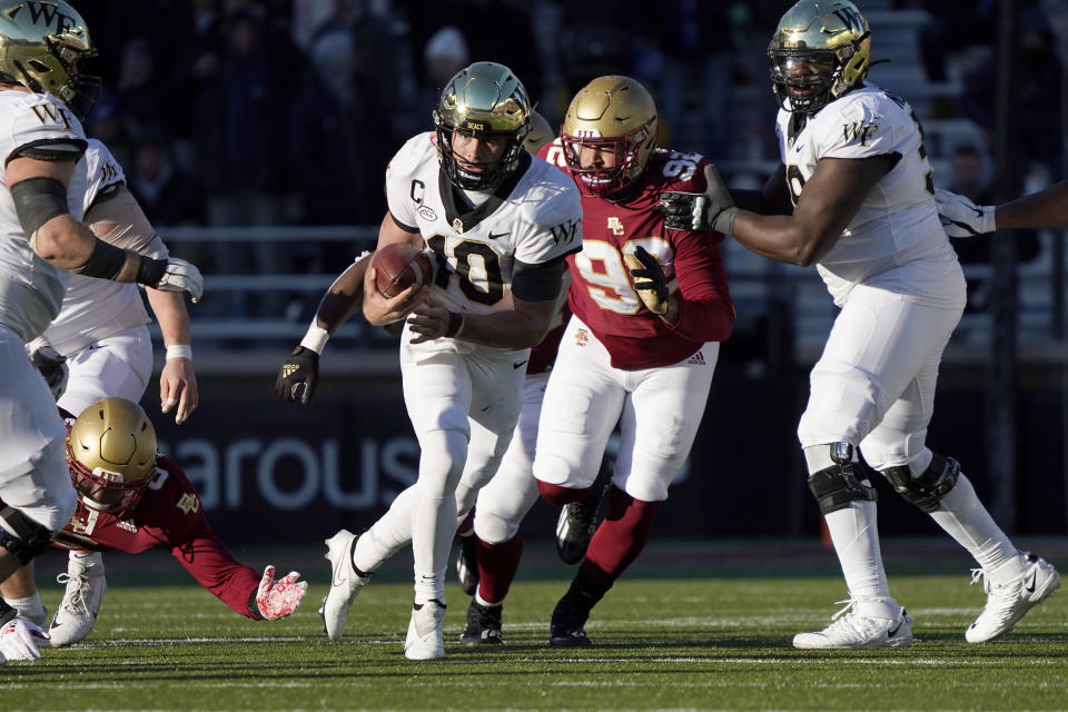 Wake Forest quarterback Sam Hartman (10) rushes ahead of Boston College defensive lineman Izaiah Henderson (92) during the second half of an NCAA college football game, Saturday, Nov. 27, 2021, in Boston. (AP Photo/Mary Schwalm)