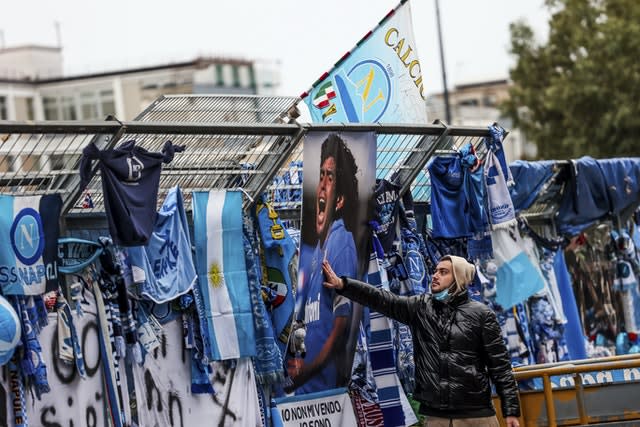 A fan touches a photo of Diego Maradona hanging on the gates of Napoli's stadium