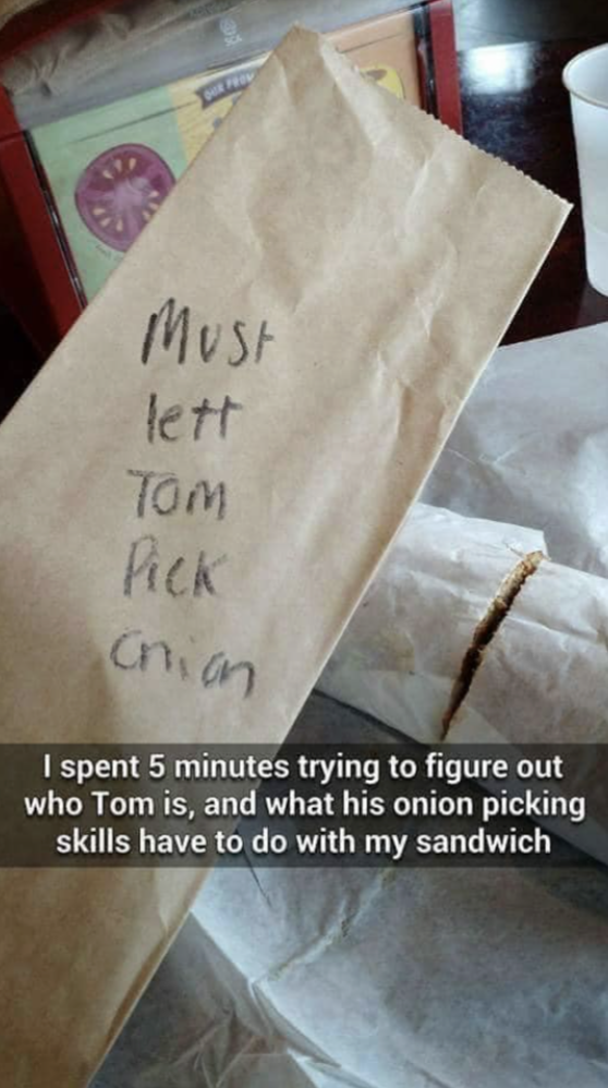 Handwritten note that says, "Must lett Tom pick an" on a sandwich bag, with humorous commentary on figuring out its meaning