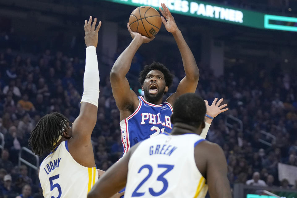 Philadelphia 76ers center Joel Embiid, top, shoots over Golden State Warriors forward sKevon Looney (5) and Draymond Green (23) during the first half of an NBA basketball game in San Francisco, Friday, March 24, 2023. (AP Photo/Jeff Chiu)