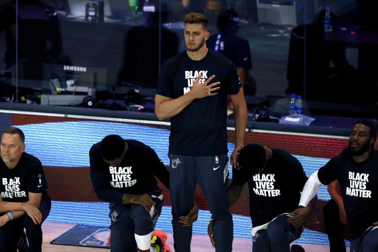 Meyers Leonard of the Miami Heat stands for the national anthem while his teammates kneel.