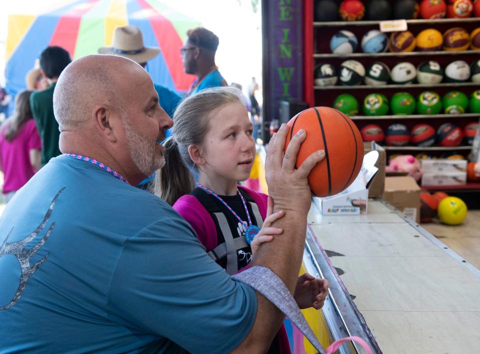 John Sulawski helps his daughter Madison Sulawski shoot a basketball during Special Kids Days at the West Side Nut Club’s Fall Festival in Evansville, Ind., Tuesday morning , Oct. 4, 2022.